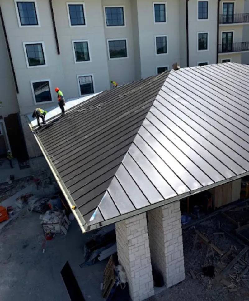 Crew installing standing seam metal roof panels on a commercial project in Hickory